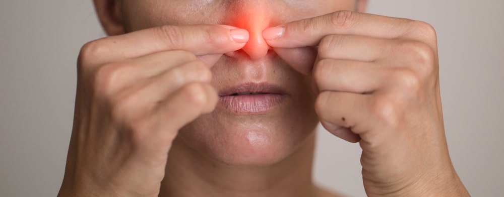 Close-up of person with glowing red nose indicating sinus problems that need treatment.